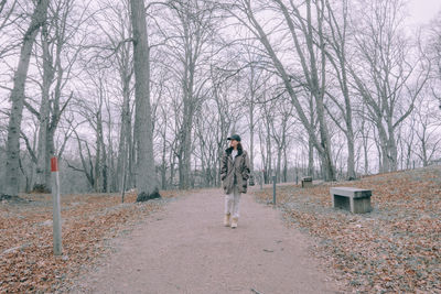 Full length of woman standing in snow covered forest