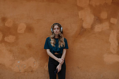 Portrait of a young woman standing against wall