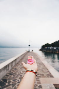 Midsection of person with hand against sea against sky