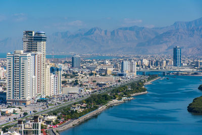 Aerial view of city by sea against sky