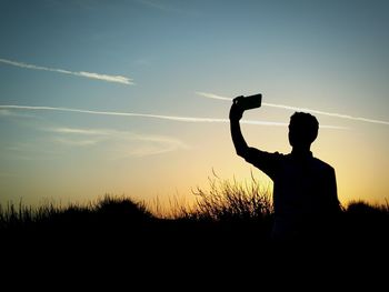 Silhouette people on field at sunset