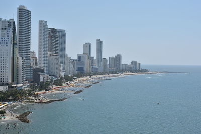 Sea by cityscape against clear sky