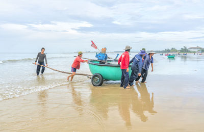 People enjoying at beach against sky