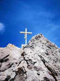 Low angle view of cross on rock against sky