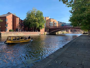 Bridge over river by buildings in city against sky