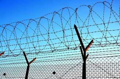 Close-up of barbed wire fence against sky