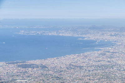 Aerial view of city by sea against sky