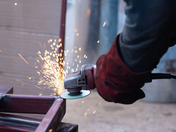 Midsection of man working on illuminated metal