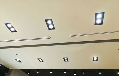 Low angle view of illuminated lights on ceiling of building