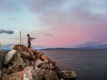 Rock formation by sea against sky during sunset