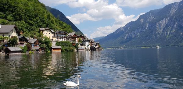 Houses by lake and mountains against sky