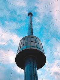 Low angle view of communications tower against cloudy sky