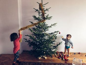 Children decorating christmas tree at home
