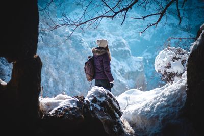 Rear view of woman standing on rock during winter