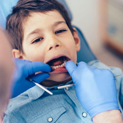 Cropped image of dentist examining boy at clinic