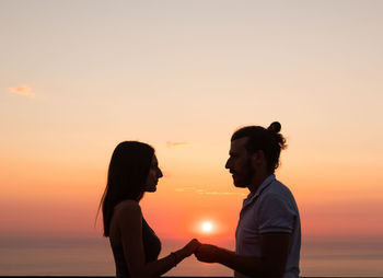 Silhouette people against sea during sunset