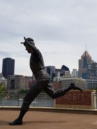 Statue against modern buildings in city against sky