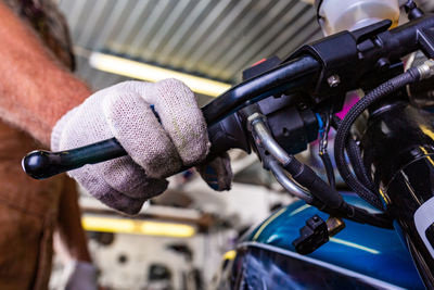 Midsection of mechanic repairing motorcycle in garage