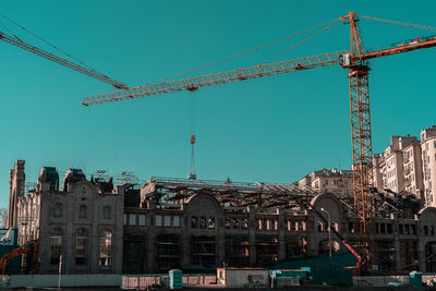 Cranes at construction site against sky in city