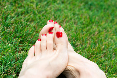 Low section of woman with hand on grass