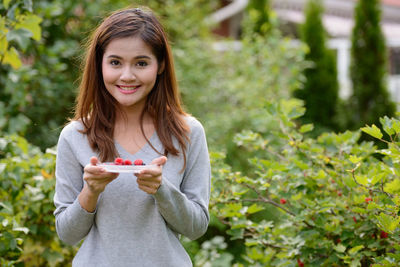 Portrait of smiling woman holding food outdoors