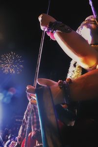 Low angle view of hand holding firework display at night