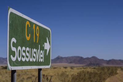 Information sign on road against clear blue sky