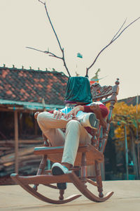 Low angle view of man with pot covered face sitting against sky