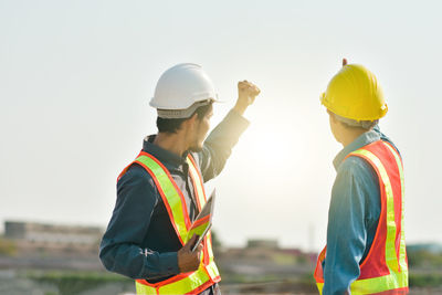 People working with umbrella standing against sky