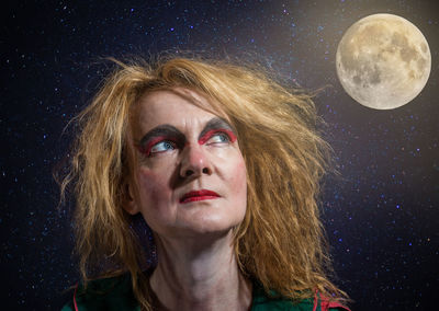 Close-up of woman with make-up against moon