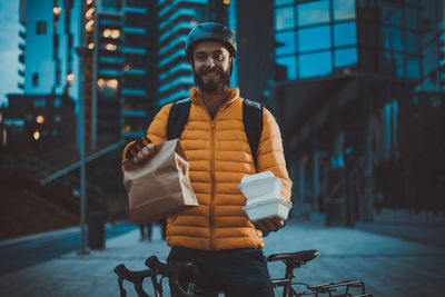 Portrait of man standing with bicycle on street in city