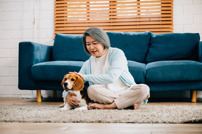 Portrait of woman with dog sitting on sofa at home