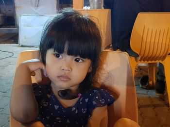 Portrait of cute girl sitting on chair at home
