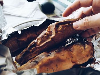 Cropped image of hand holding roasted sweet potato