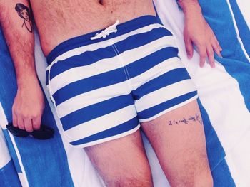 Midsection of man in swimming shorts relaxing on towel