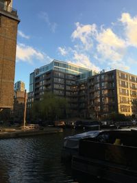 Buildings by river against sky in city