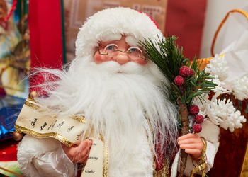 Santa claus doll in front in front of presents and christmas decorations