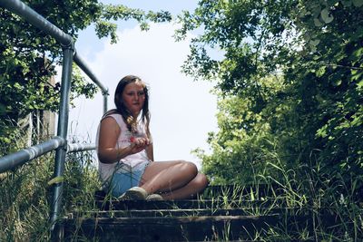 Portrait of woman sitting against trees