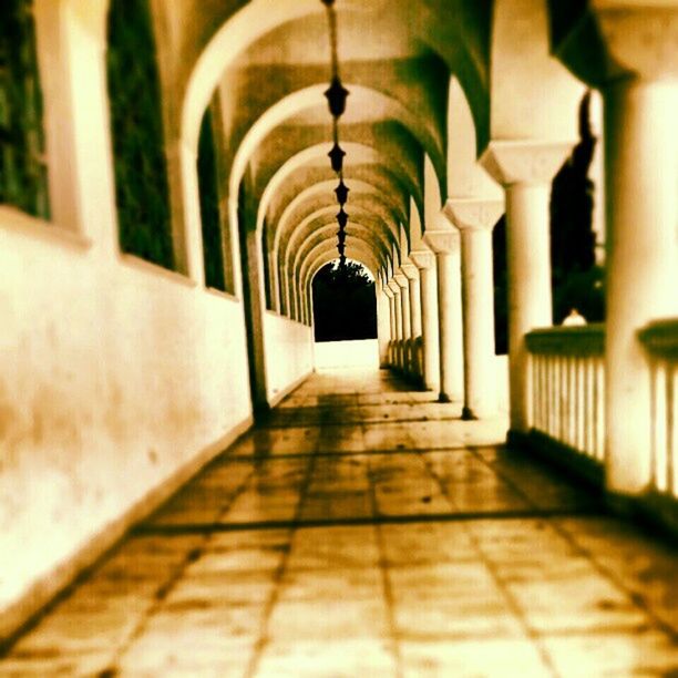 indoors, the way forward, corridor, architecture, diminishing perspective, built structure, in a row, empty, flooring, vanishing point, ceiling, colonnade, lighting equipment, tiled floor, architectural column, illuminated, absence, arch, narrow, walkway