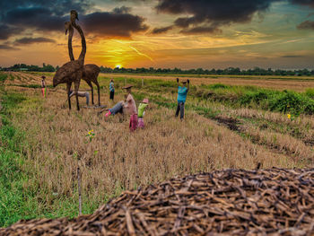 People on field against sky during sunset