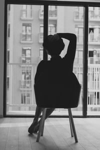 Rear view of woman sitting on chair at home