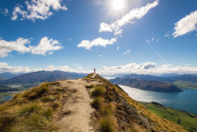 Distant view of woman standing on mountain against sky