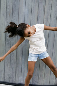 Playful girl standing against wooden wall