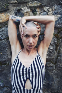 Portrait of young woman standing against wall