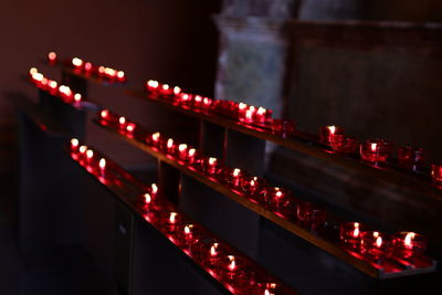 High angle view of red lit tea light candles in church