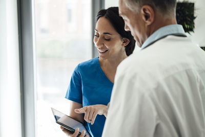 Smiling nurse discussing with doctor over tablet pc in hospital