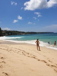 People on beach against sky during sunny day