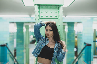 Portrait of young woman standing against blurred background