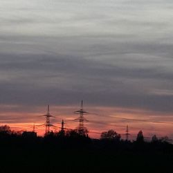 Silhouette of electricity pylon against dramatic sky