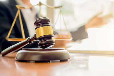 Midsection of judge working at desk with gavel and weight scale